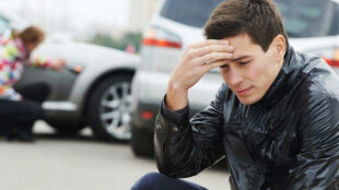 Young man sitting beside the scene of an accident. Copyright: Dmitry Kalinovsky