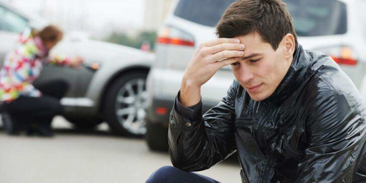 Young man sitting beside the scene of an accident. Copyright: Dmitry Kalinovsky